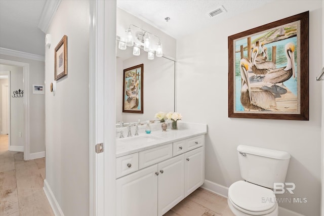 bathroom with toilet, wood finished floors, vanity, visible vents, and baseboards