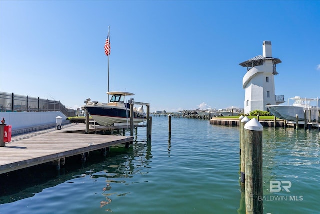 view of dock featuring a water view, boat lift, and fence