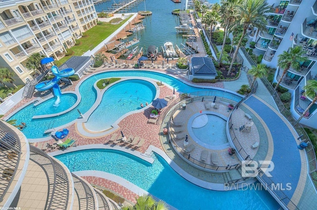 pool with a water view, a hot tub, a patio area, a water play area, and a water slide