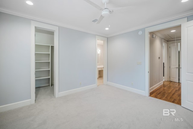 unfurnished bedroom featuring a spacious closet, crown molding, and ceiling fan