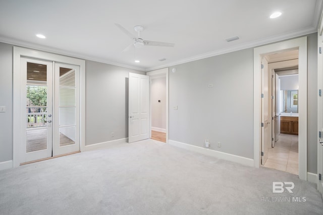 carpeted spare room with ceiling fan, ornamental molding, and french doors