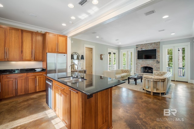 kitchen with tile flooring, a center island with sink, a fireplace, sink, and appliances with stainless steel finishes