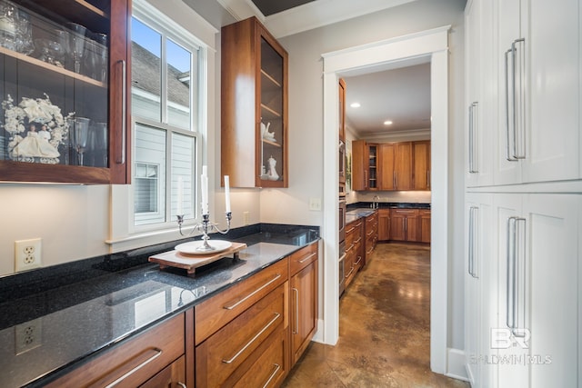 kitchen with dark stone counters, ornamental molding, a healthy amount of sunlight, and oven