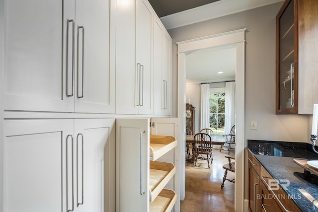 kitchen with crown molding, tile flooring, white cabinets, and dark stone countertops