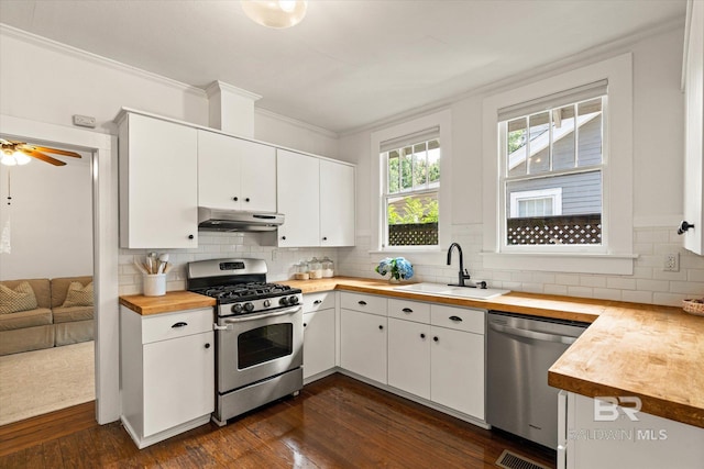 14 Macy Pl, Mobile, AL 36604 - kitchen with stainless steel appliances, wooden counters, under cabinet range hood, decorative backsplash, and crown molding