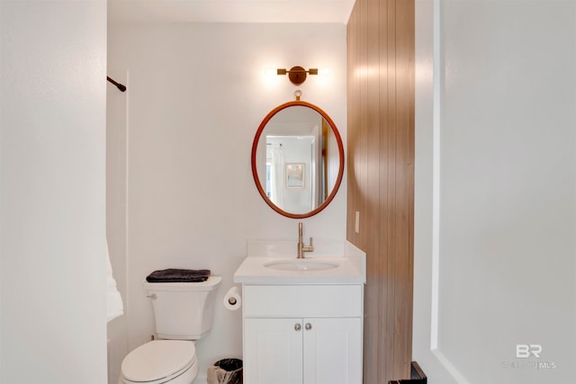 bathroom featuring toilet, vanity, and wooden walls