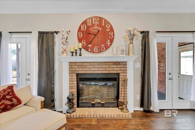 living area featuring dark wood-style flooring, a healthy amount of sunlight, crown molding, and a fireplace