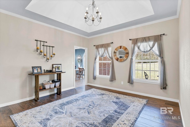 foyer entrance with a raised ceiling, a notable chandelier, baseboards, and hardwood / wood-style flooring