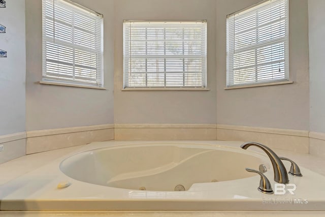 bathroom with a tub with jets and a wealth of natural light