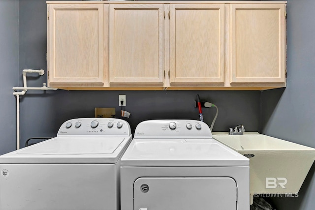 clothes washing area featuring cabinet space, washer and clothes dryer, and a sink