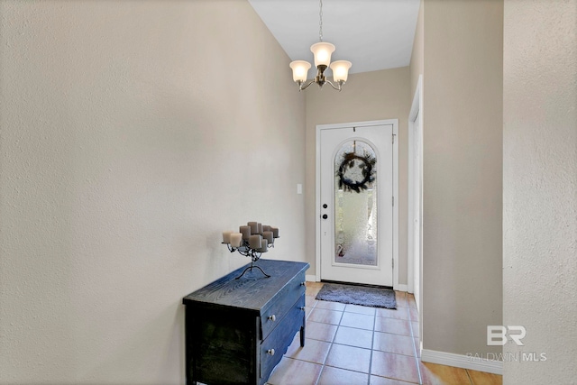 entrance foyer with baseboards, light tile patterned flooring, and an inviting chandelier