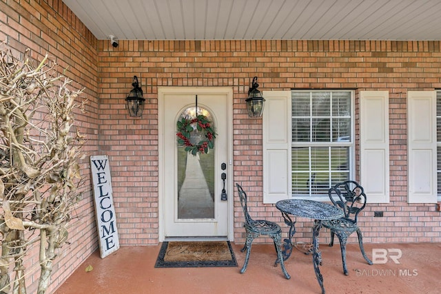 entrance to property with covered porch and brick siding