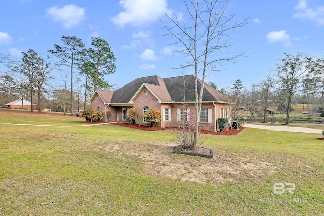 view of front facade featuring a shingled roof, a front lawn, and brick siding