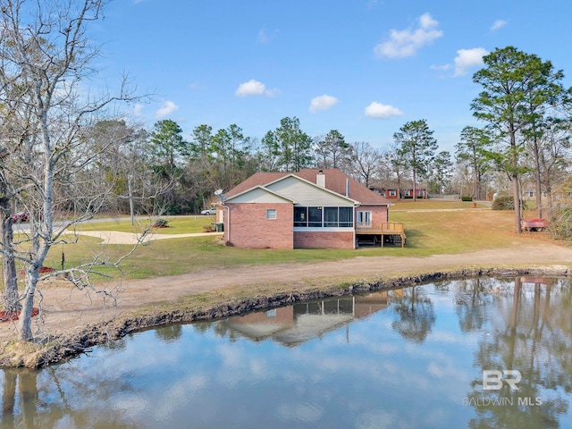 exterior space featuring brick siding, a yard, a water view, a sunroom, and driveway