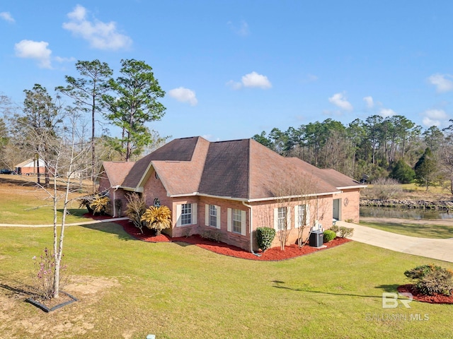 view of side of property with driveway, roof with shingles, a yard, central AC, and brick siding