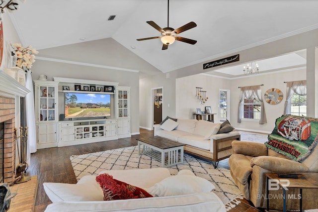 living room with crown molding, a fireplace, wood-type flooring, visible vents, and ceiling fan with notable chandelier