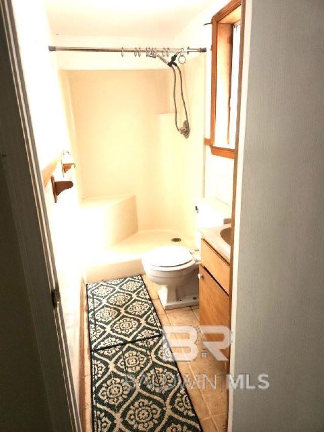 full bath featuring tile patterned floors, toilet, a shower, and vanity