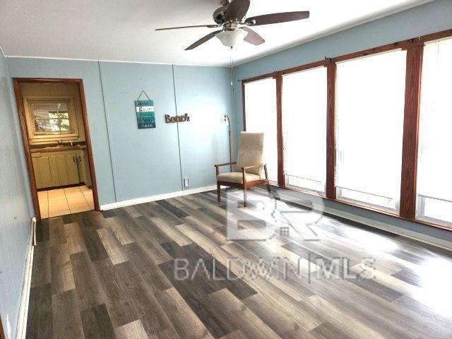 unfurnished room with baseboards, a ceiling fan, and wood finished floors