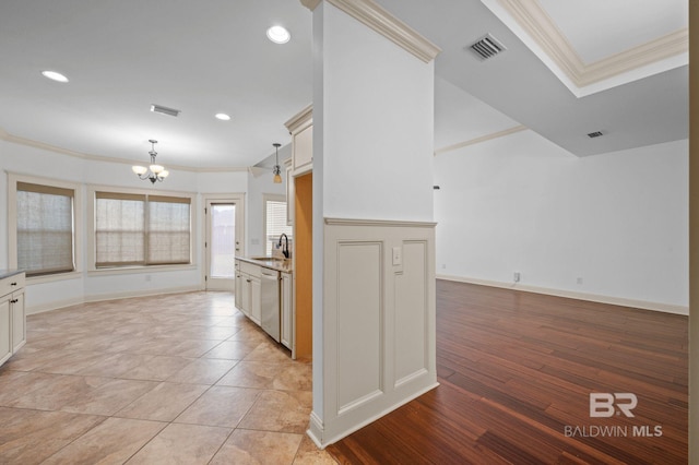 kitchen with stainless steel dishwasher, decorative light fixtures, light hardwood / wood-style floors, and crown molding