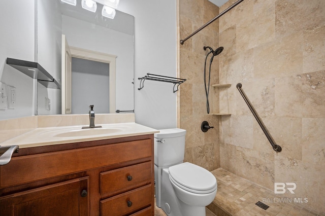 bathroom with vanity, toilet, and tiled shower