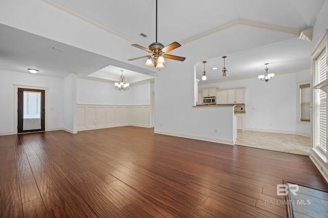 unfurnished living room with ceiling fan with notable chandelier, dark hardwood / wood-style flooring, and ornamental molding