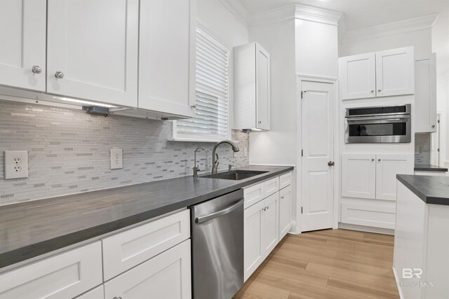4340 Hamilton Oaks Ln, Mobile, AL 36695 - kitchen with appliances with stainless steel finishes, crown molding, white cabinets, tasteful backsplash, and light wood-style floors