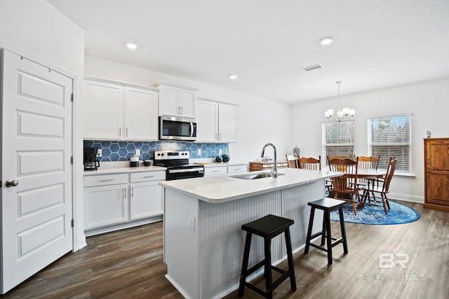 kitchen featuring stainless steel appliances, decorative light fixtures, sink, and white cabinets