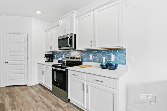 kitchen featuring appliances with stainless steel finishes, white cabinets, light wood-type flooring, and decorative backsplash