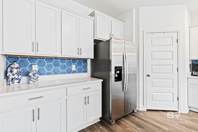 kitchen featuring stainless steel refrigerator with ice dispenser, white cabinetry, hardwood / wood-style floors, and decorative backsplash