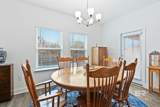 dining area with wood-type flooring and a notable chandelier