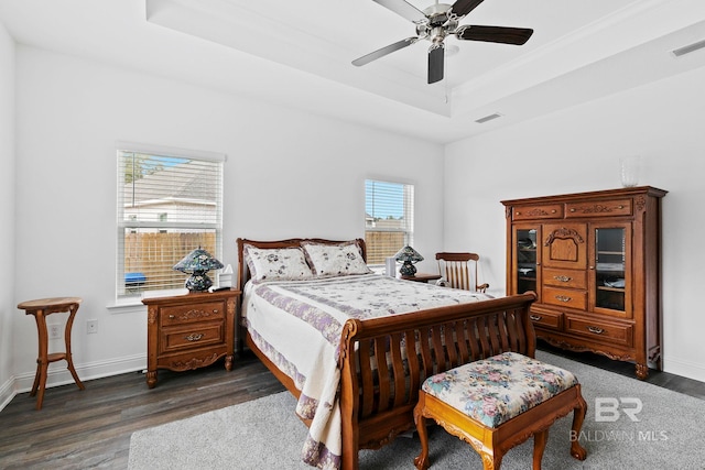 bedroom featuring dark hardwood / wood-style floors, ceiling fan, and a tray ceiling