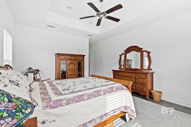 bedroom featuring a raised ceiling, ceiling fan, crown molding, and dark hardwood / wood-style flooring