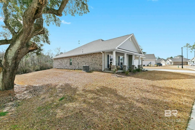 view of side of home with central AC, a porch, and a yard