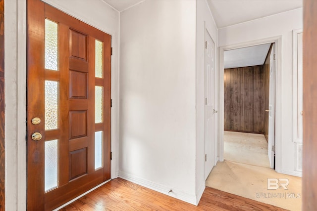 foyer entrance featuring light wood-style flooring, wooden walls, and baseboards