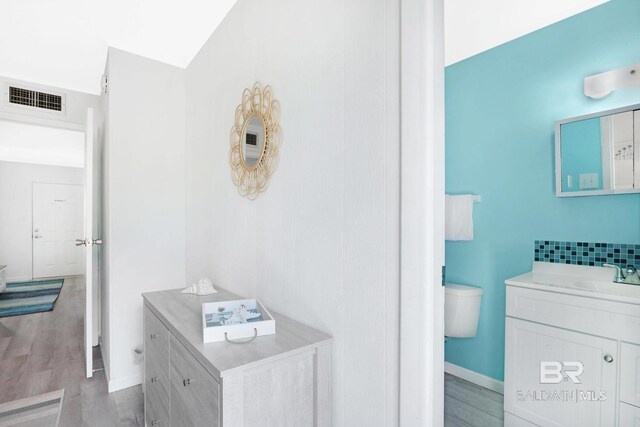 325 E 22nd Ave Unit 4, Gulf Shores, AL 36542 - bathroom featuring vanity, wood finished floors, visible vents, baseboards, and toilet