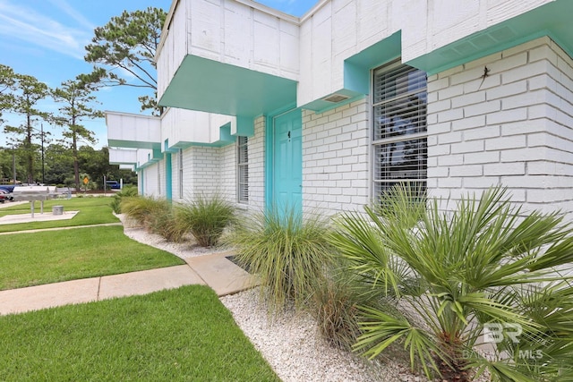 view of exterior entry with a yard and brick siding