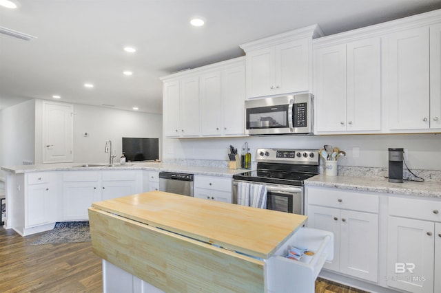 kitchen with appliances with stainless steel finishes, white cabinetry, a sink, and a peninsula