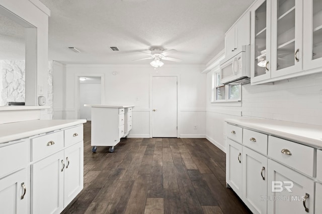 kitchen with white cabinetry, a textured ceiling, dark hardwood / wood-style flooring, ceiling fan, and backsplash