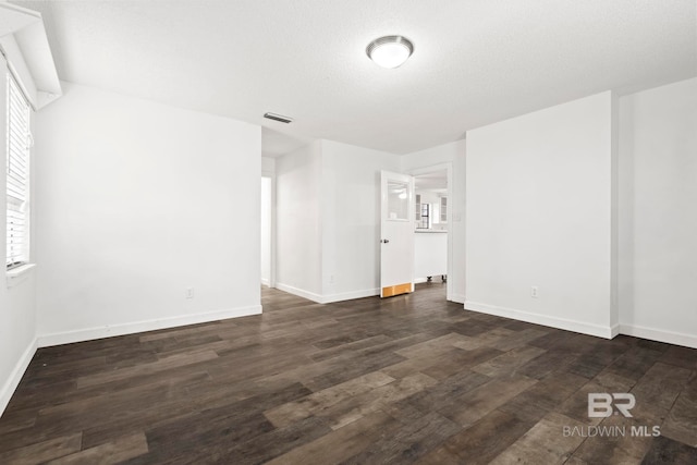 empty room with dark wood-type flooring and a textured ceiling