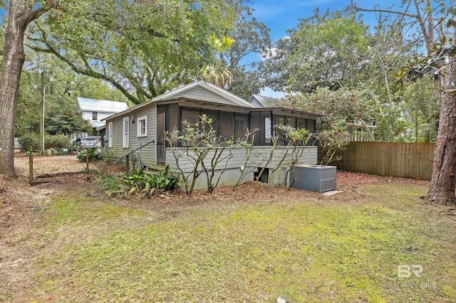 exterior space with a sunroom, cooling unit, fence, and a lawn