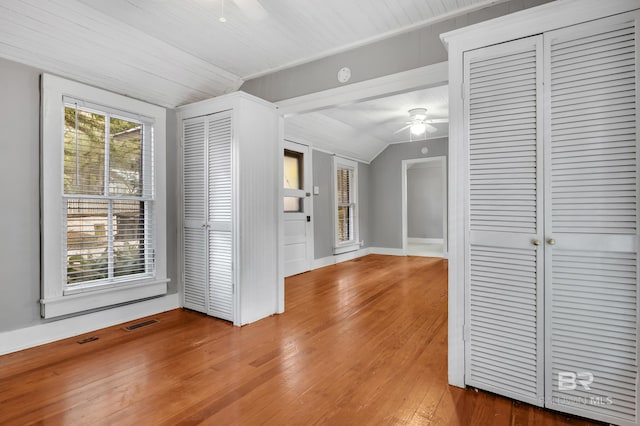 interior space with visible vents, baseboards, wood-type flooring, ceiling fan, and vaulted ceiling