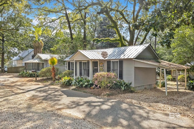 view of front of home with a standing seam roof, metal roof, driveway, and crawl space