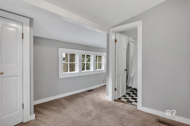 interior space featuring lofted ceiling, carpet flooring, visible vents, and baseboards