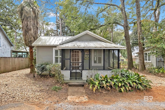 bungalow-style home featuring a sunroom, covered porch, metal roof, and fence