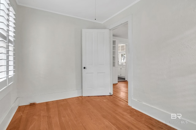 unfurnished room with ornamental molding, baseboards, and wood finished floors