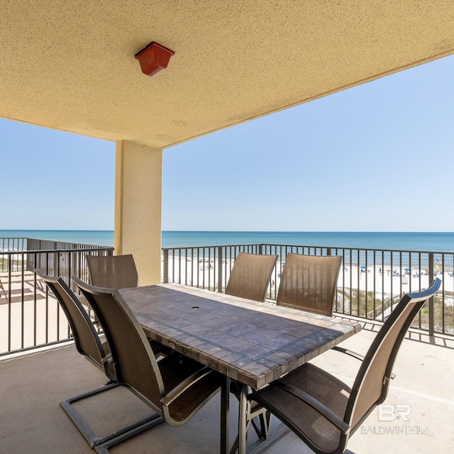 view of patio with outdoor dining space, a beach view, and a water view