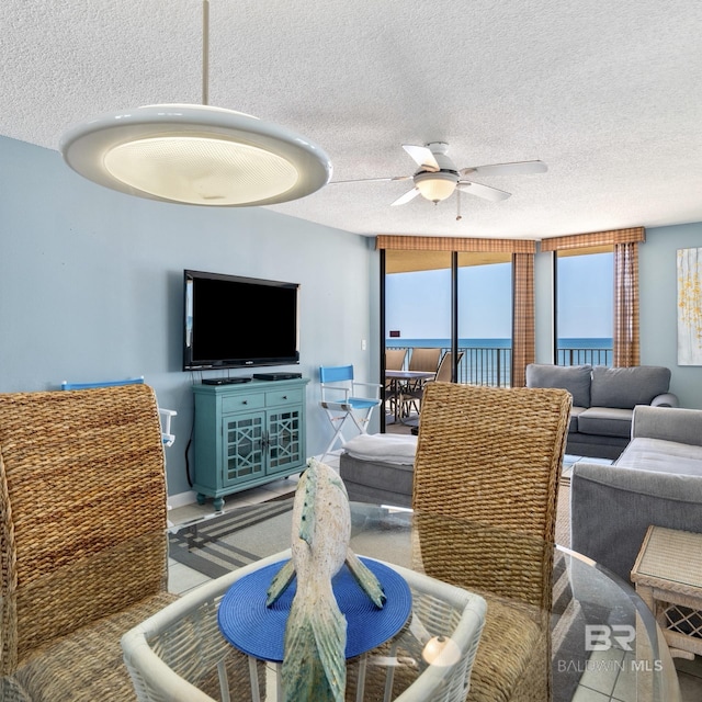 living area with a textured ceiling and ceiling fan