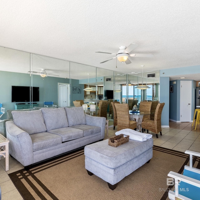 tiled living area with a textured ceiling, visible vents, and ceiling fan