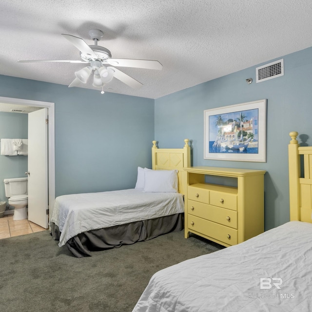 carpeted bedroom featuring visible vents, a ceiling fan, a textured ceiling, connected bathroom, and tile patterned flooring