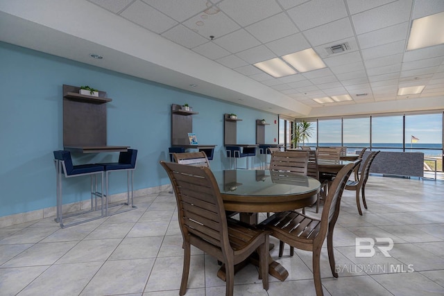 dining space featuring a drop ceiling, visible vents, baseboards, and light tile patterned floors